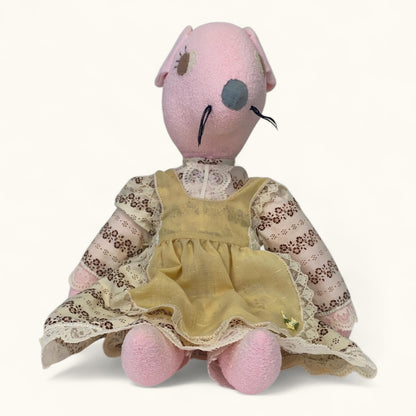 Stuffed animal toy with a pink head and yellow dress on a white background