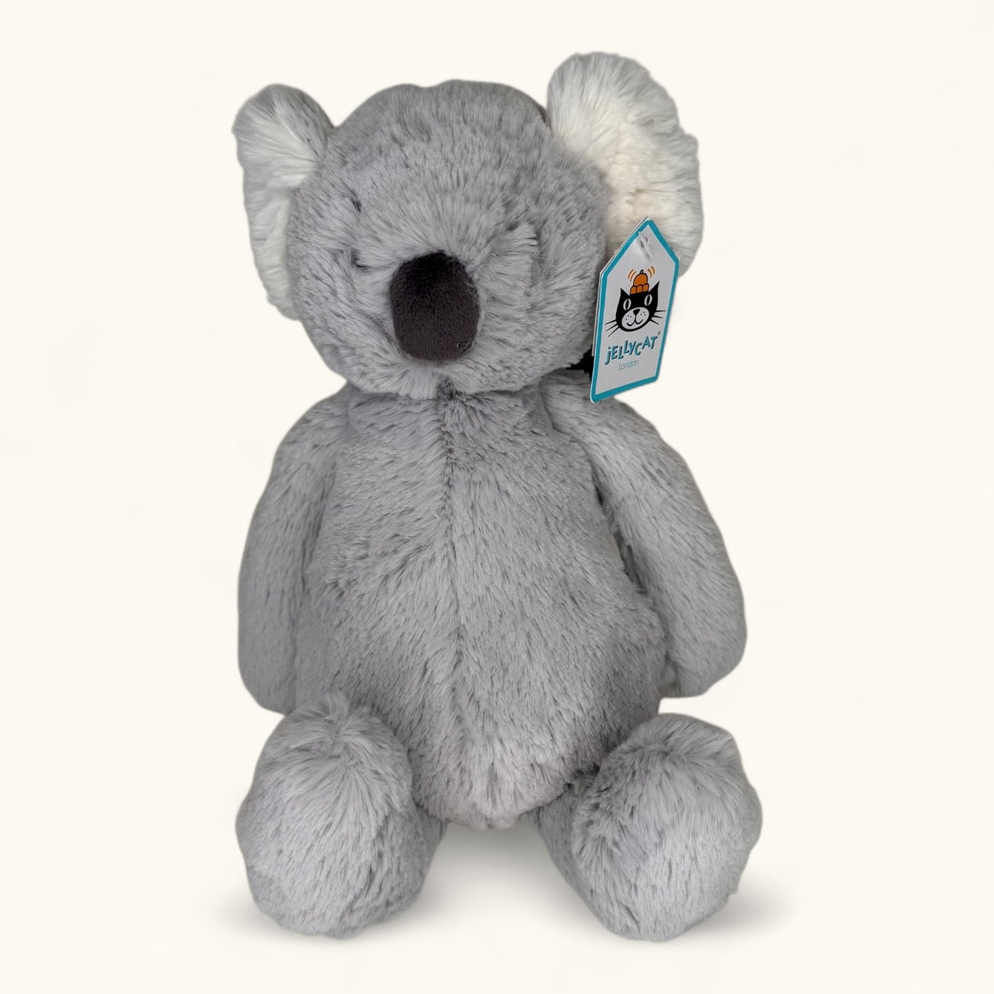 Gray plush koala toy with a visible brand tag on a white background