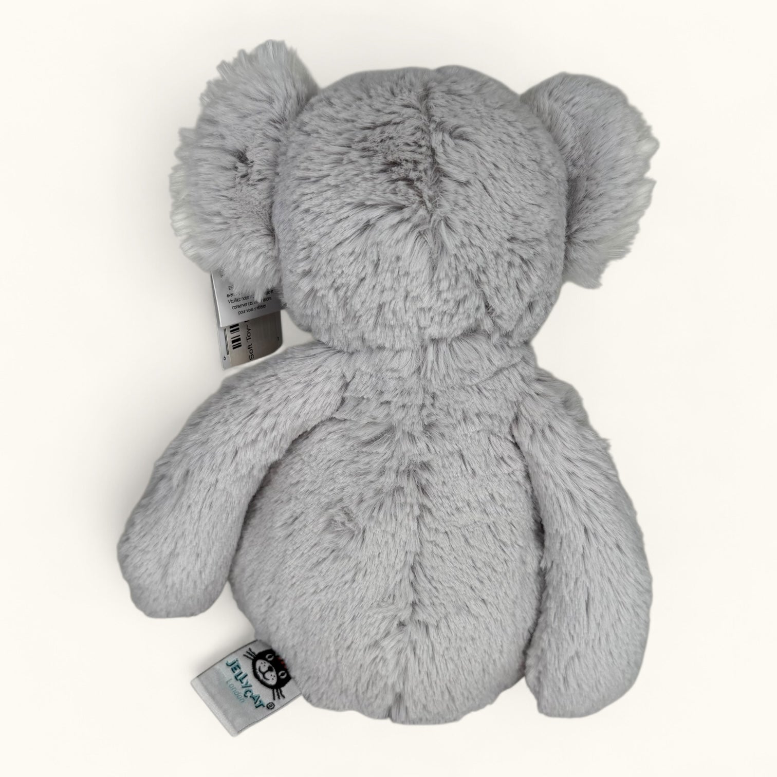 Gray plush toy with a tag on a white background