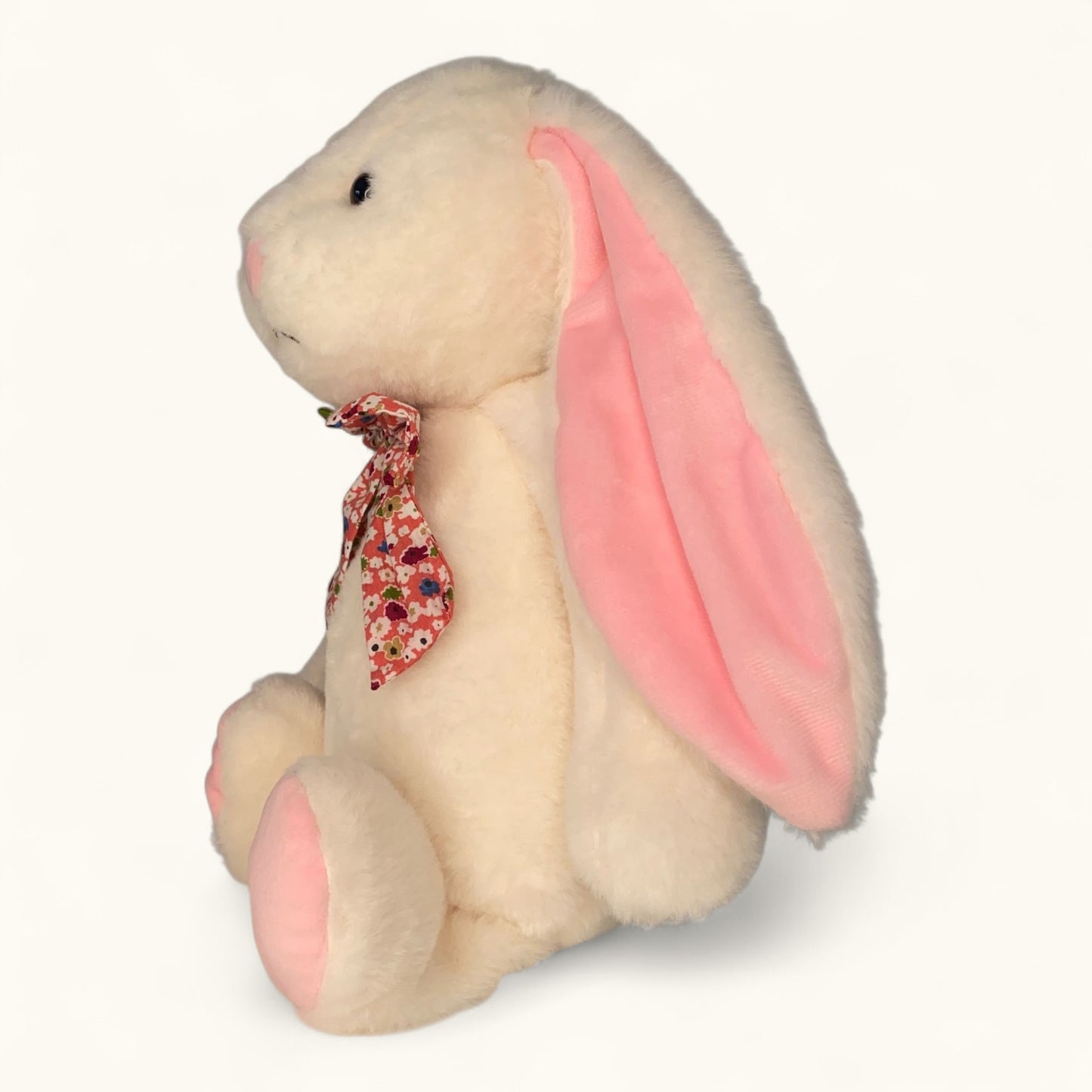 Stuffed bunny toy with pink ears and a floral bow on a white background