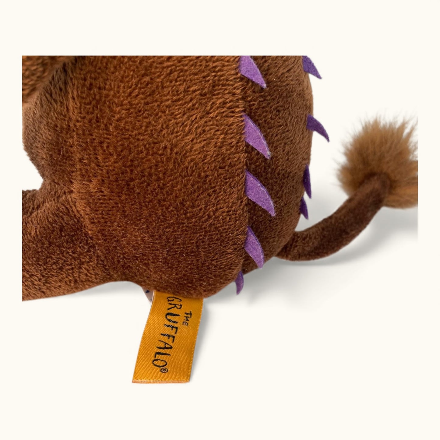 Plush toy resembling a creature from 'The Gruffalo' with a visible brand tag on a white background