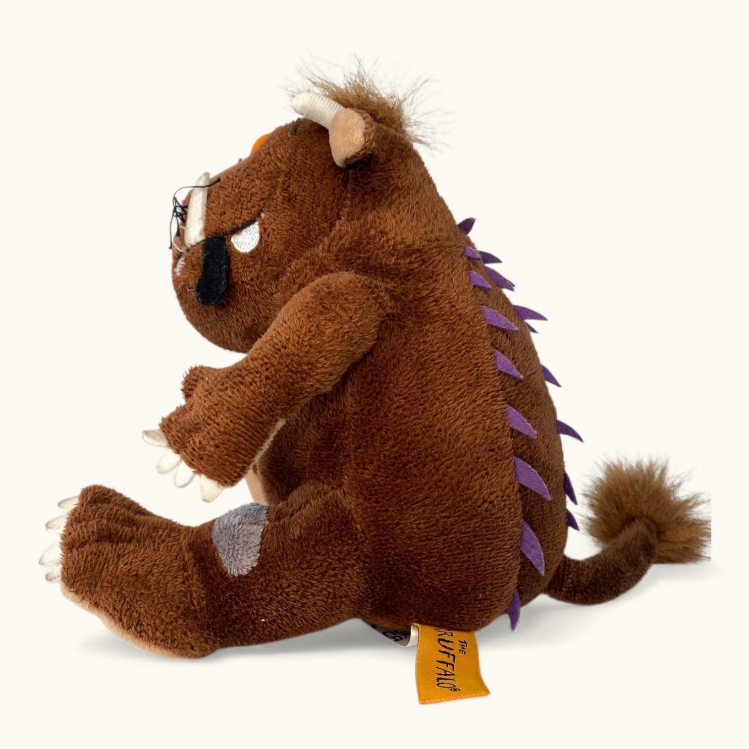 Plush toy resembling a brown creature with purple spikes on a white background