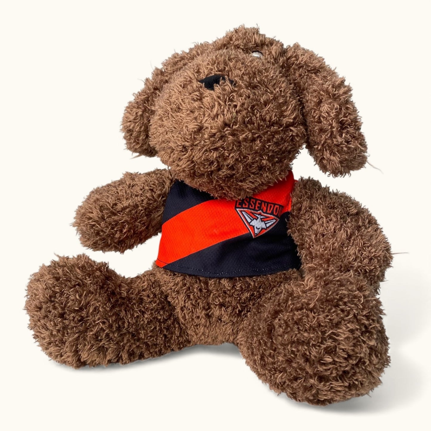 Brown teddy bear wearing a red and black bandana on a white background