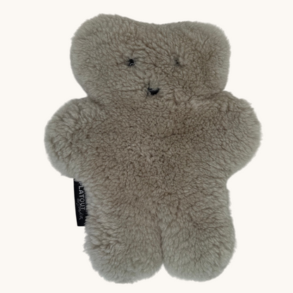 A light gray fluffy teddy bear-shaped plush toy with embroidered facial features and a small black fabric tag on the side, shown against a plain off-white background.