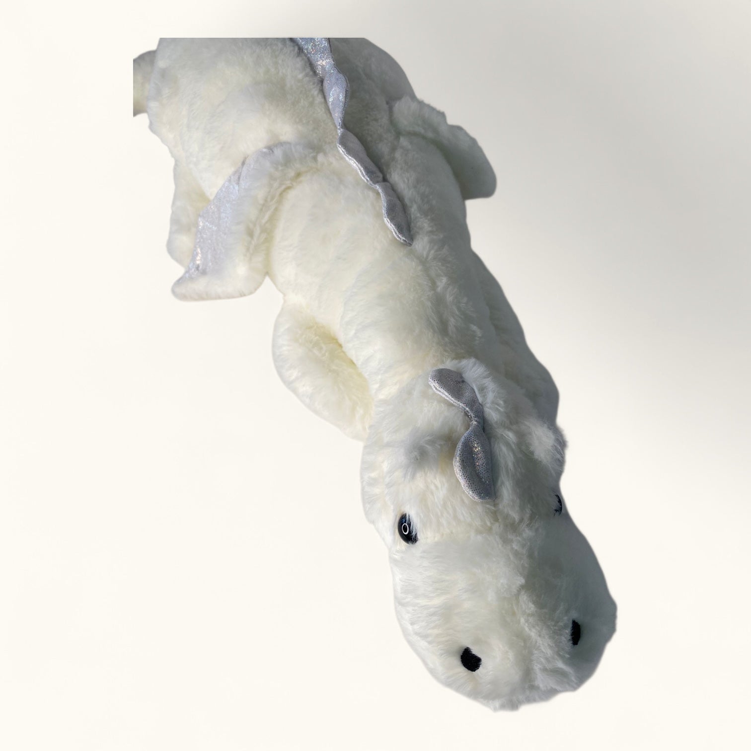 White plush toy resembling a dragon on a white background