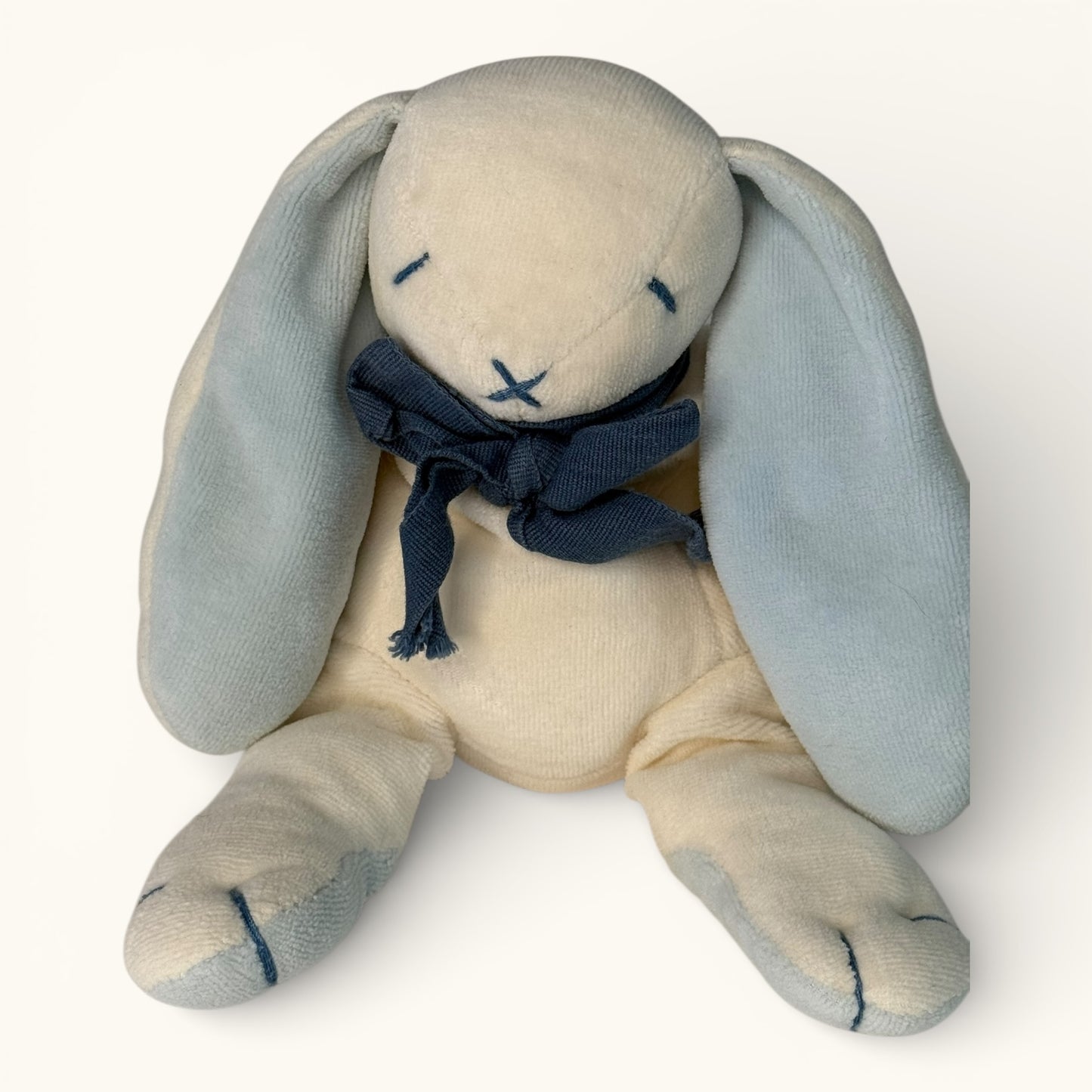 Stuffed bunny toy with a navy blue scarf on a white background