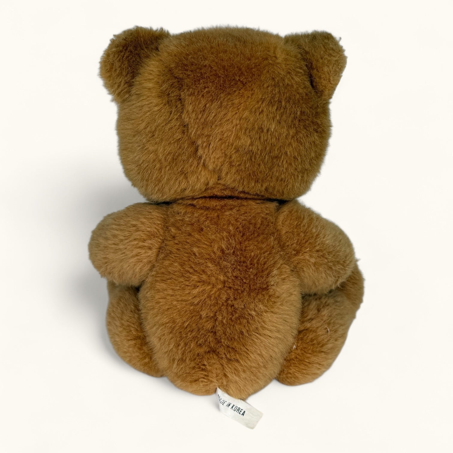 Brown teddy bear with a visible brand tag on a white background