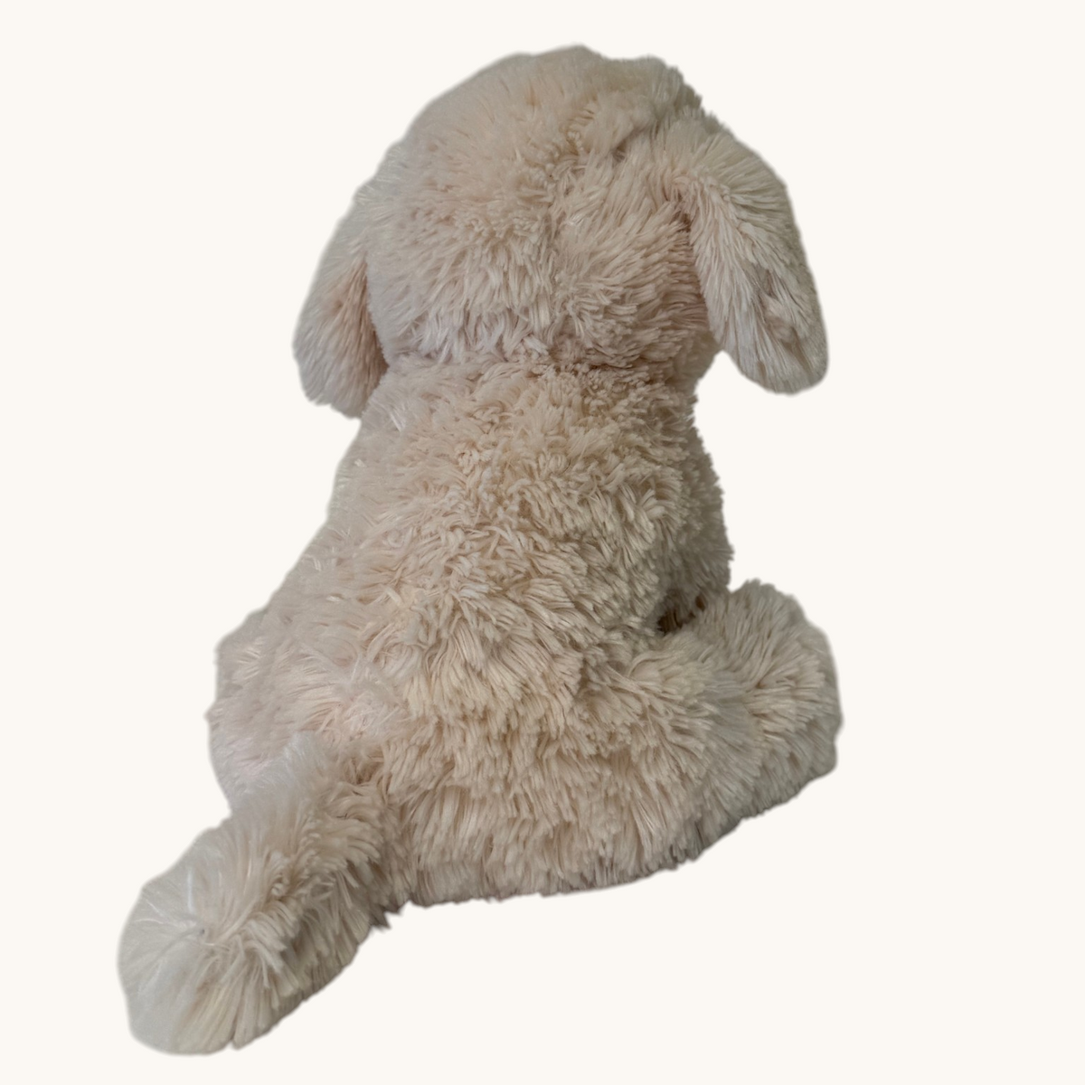 A plush dog toy with long, curly cream-colored fur, shown from behind against a plain off-white background.