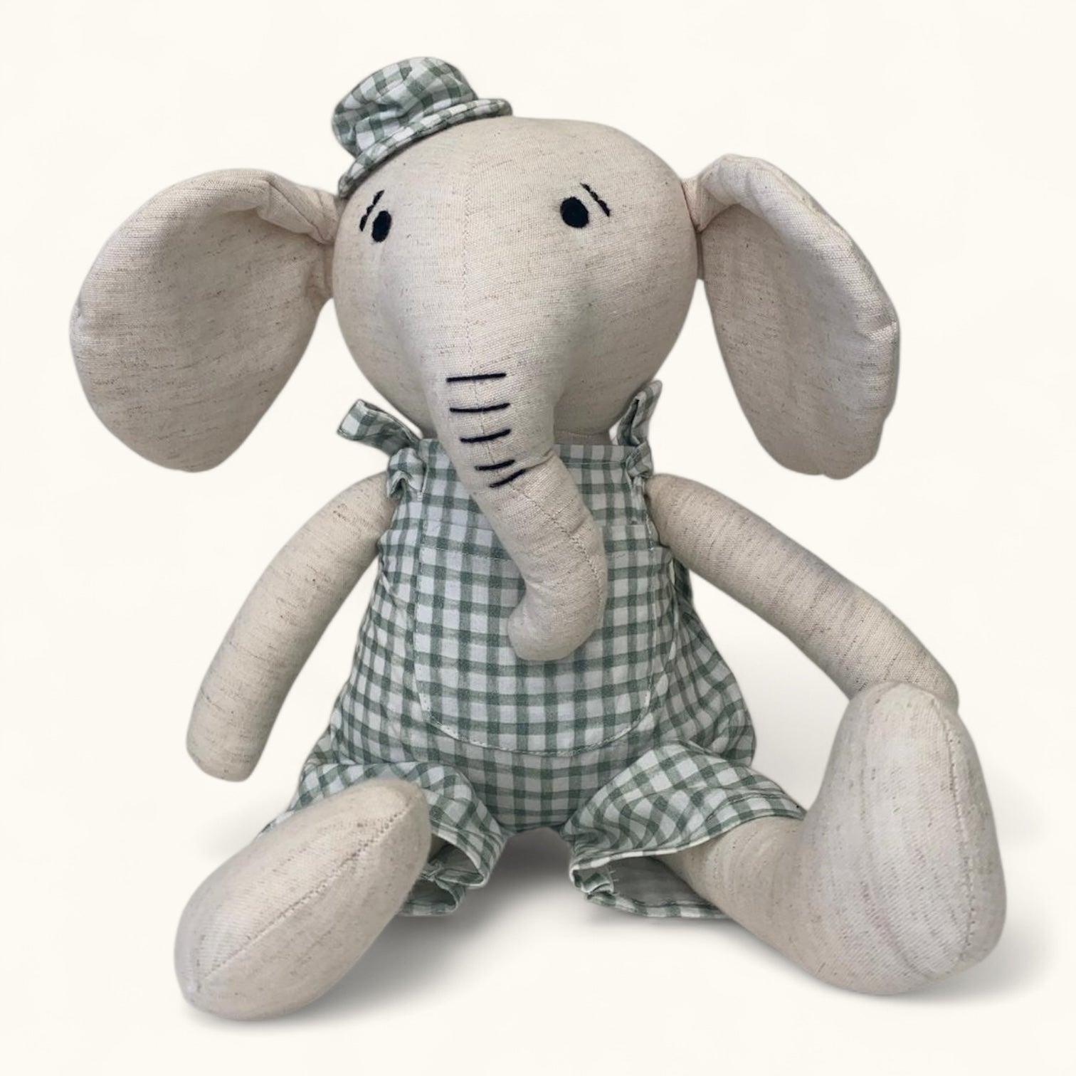 Stuffed elephant toy with a checkered outfit on a white background