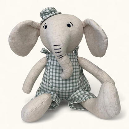 Stuffed elephant toy with a checkered outfit on a white background