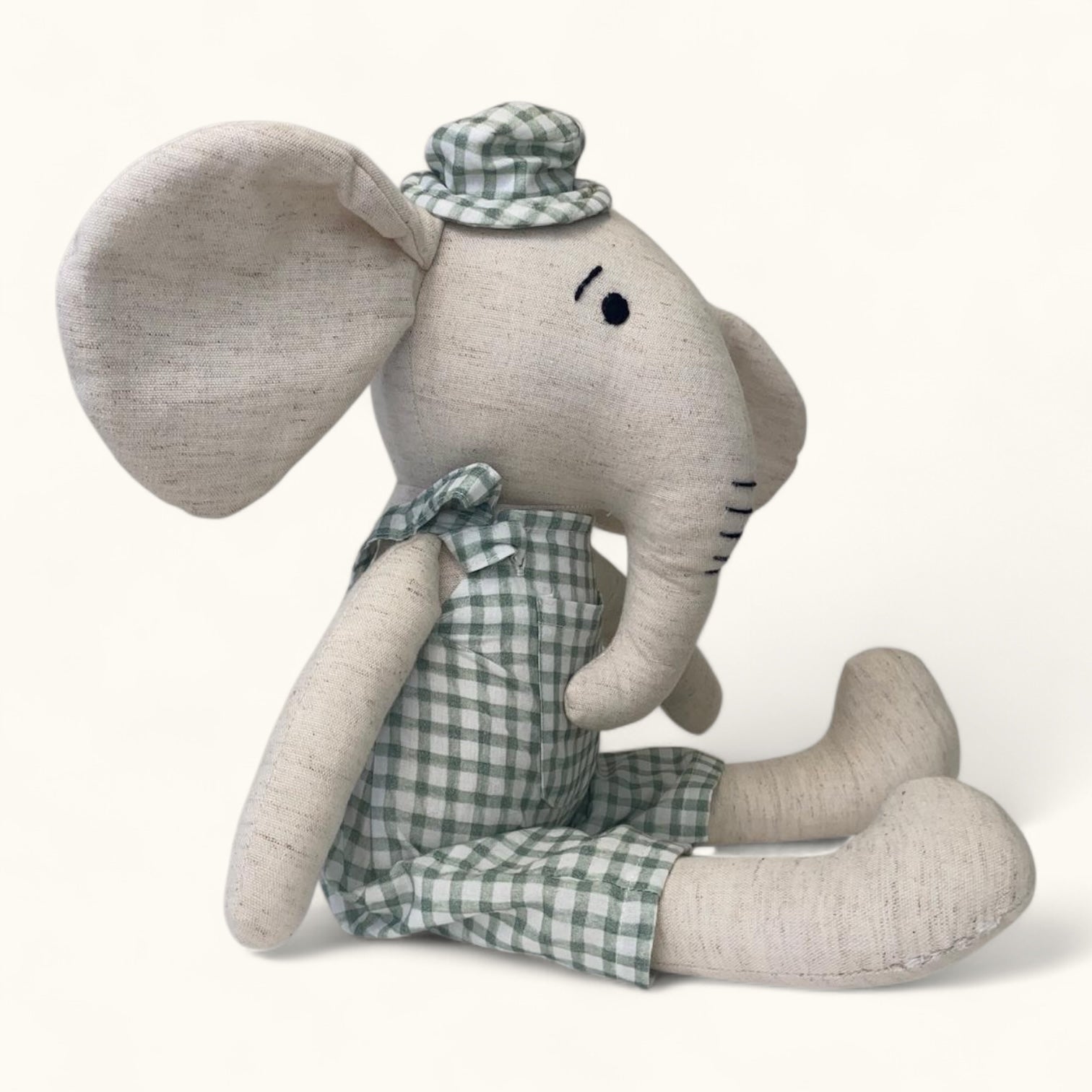 Stuffed elephant toy with a checkered outfit and hat on a white background