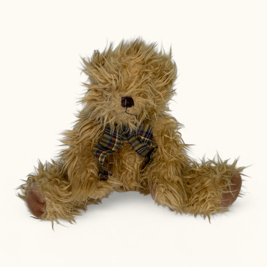 Brown teddy bear with a plaid bow tie on a white background