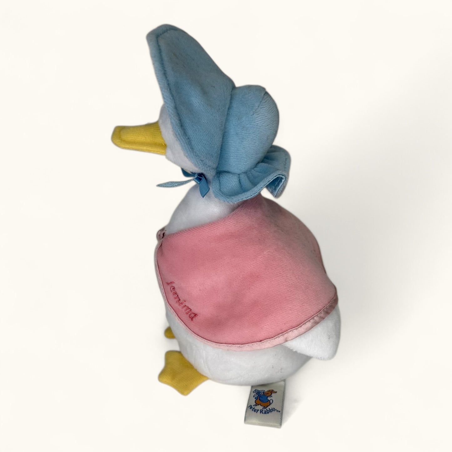 Plush toy duck with a pink outfit and blue head on a white background