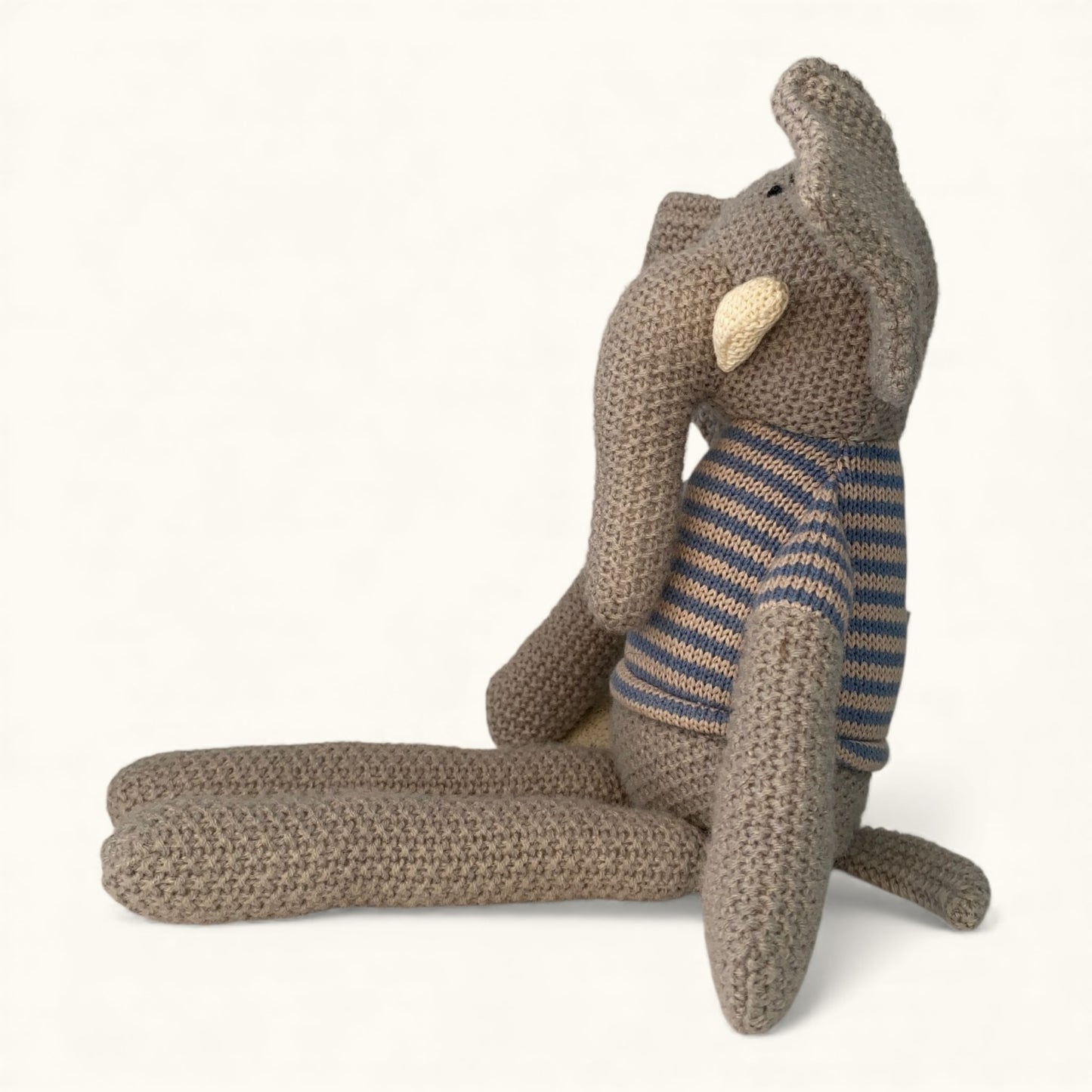 Knitted elephant toy with a striped sweater on a white background