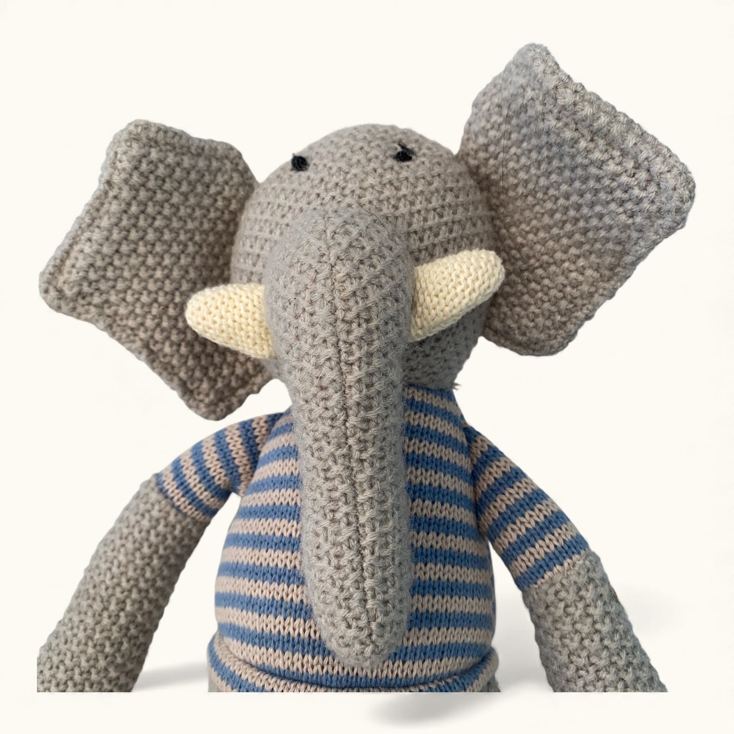 Knitted elephant toy with a striped sweater on a white background
