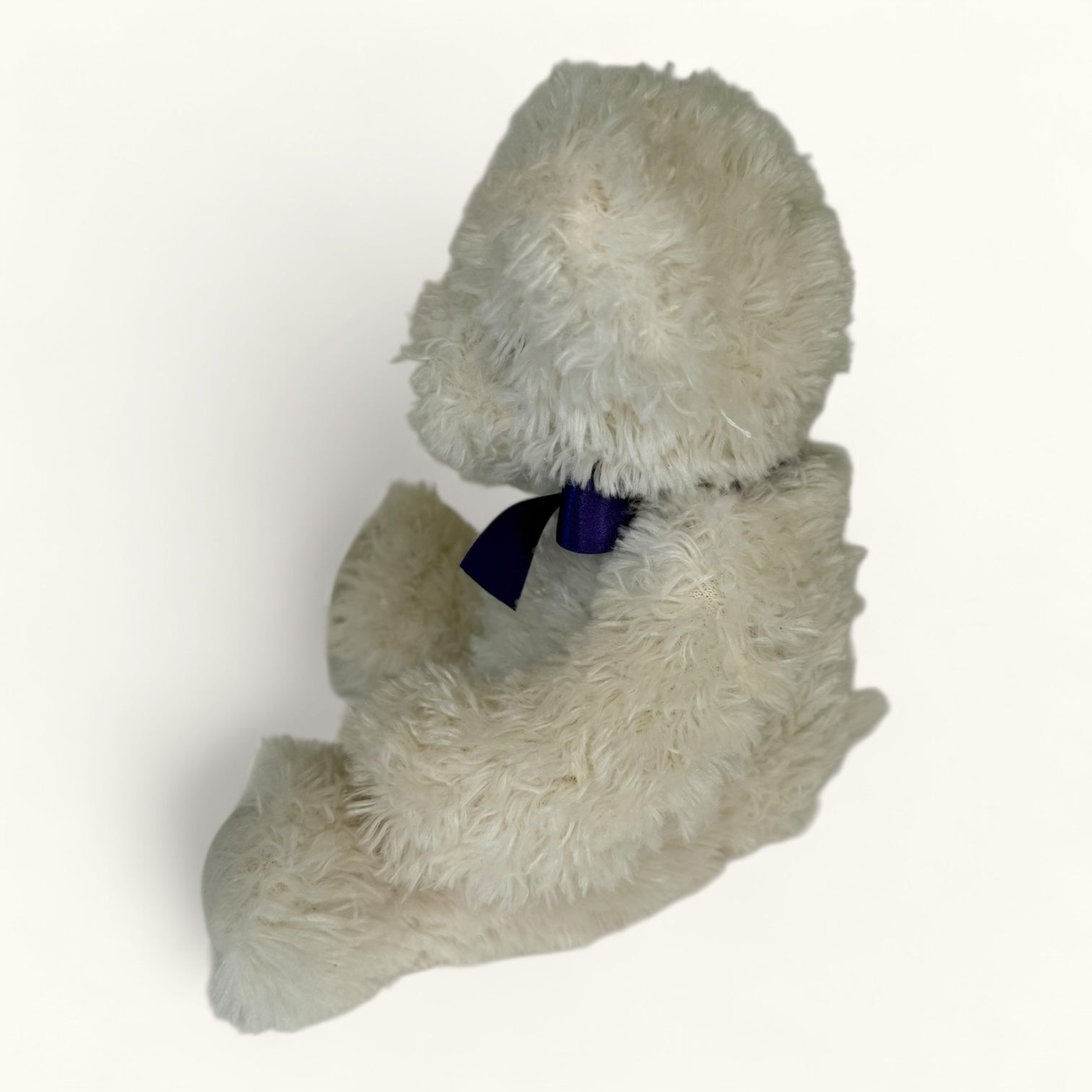 Plush toy teddy bear with a blue bow tie on a white background