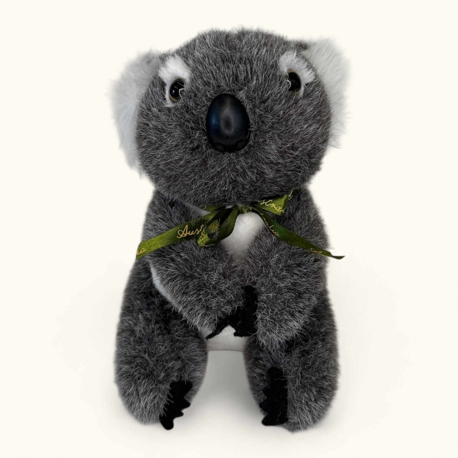 Plush koala toy with a green ribbon on a white background