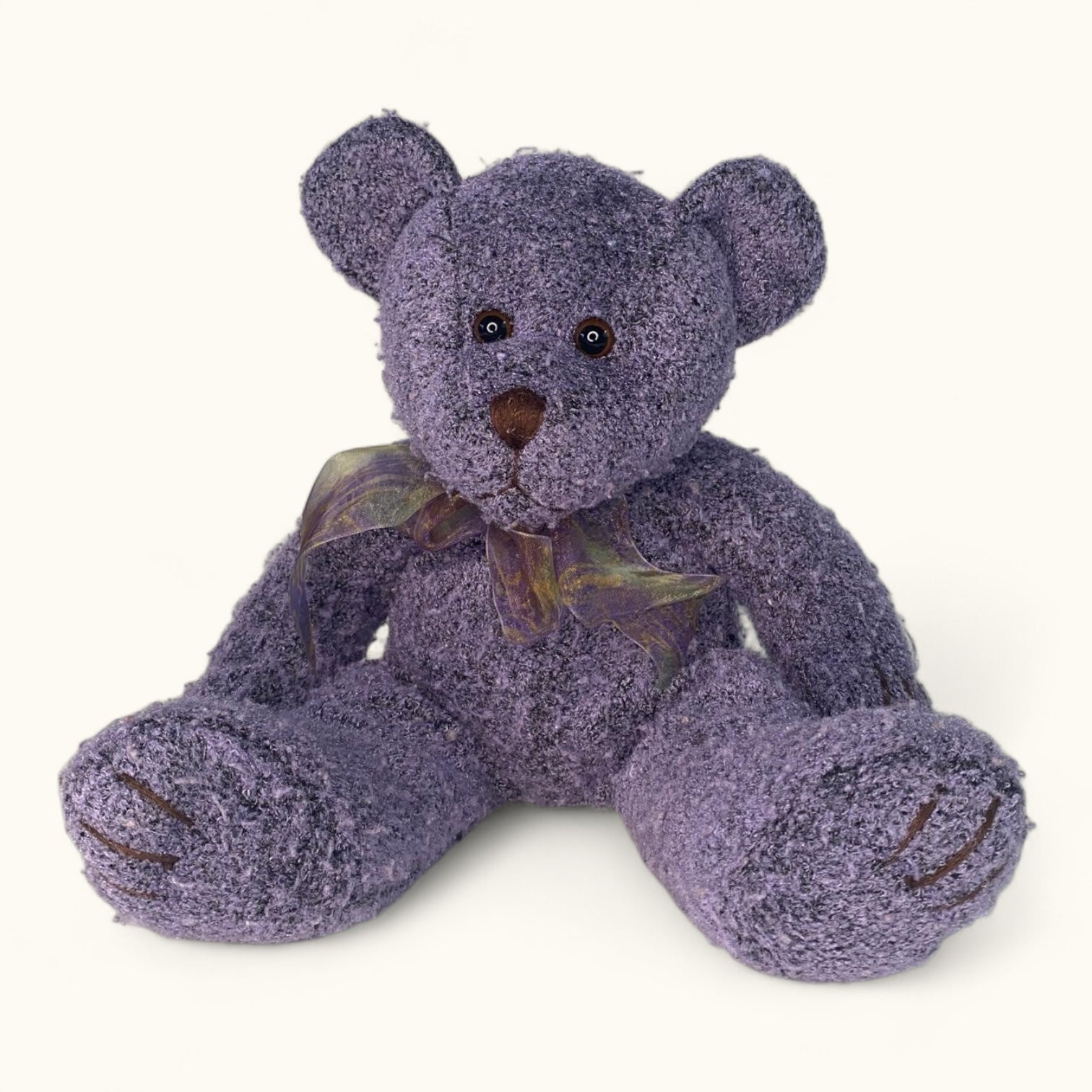 Purple teddy bear with a bow tie on a white background