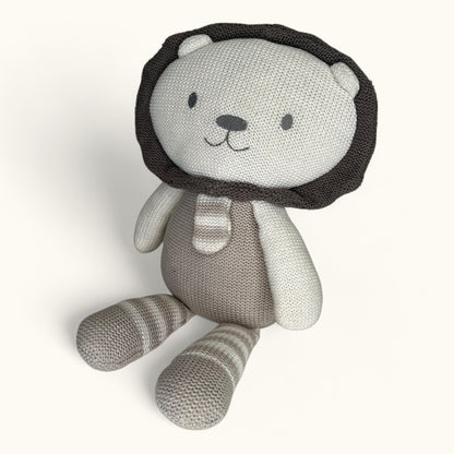 Knitted toy lion with a lion head and striped body on a white background