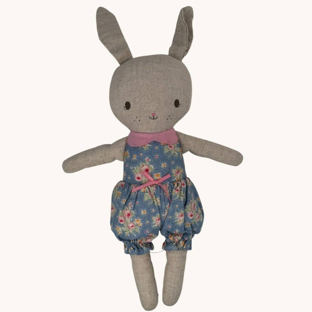 Stuffed toy rabbit wearing a floral outfit on a white background