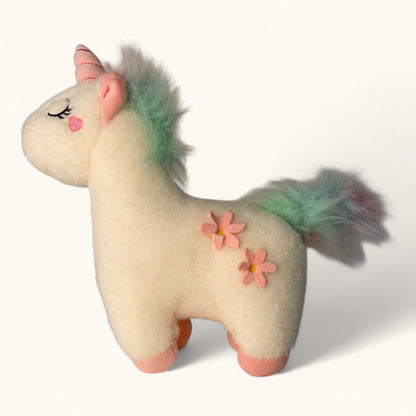 Stuffed unicorn toy with pink flowers on a white background