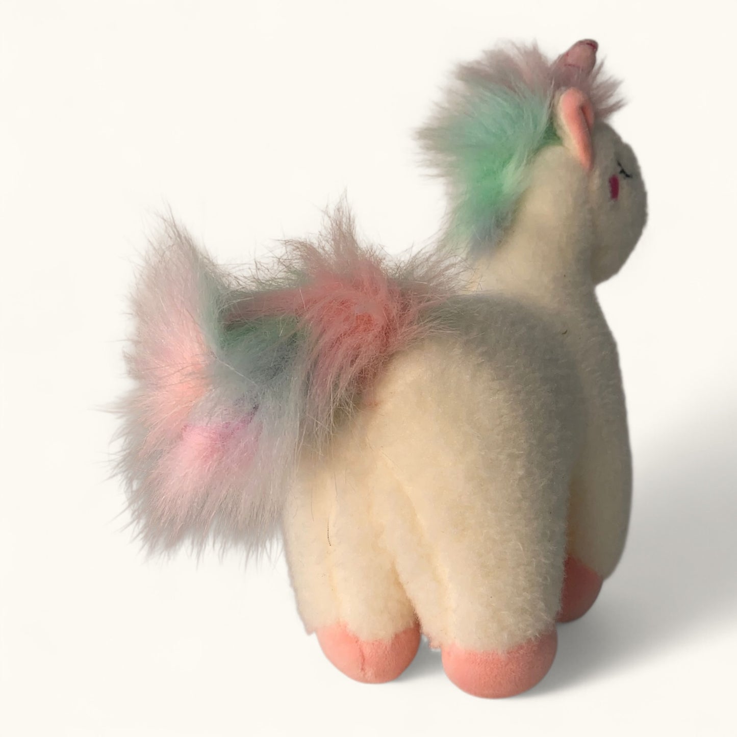 Plush toy unicorn with multicolored hair on a white background