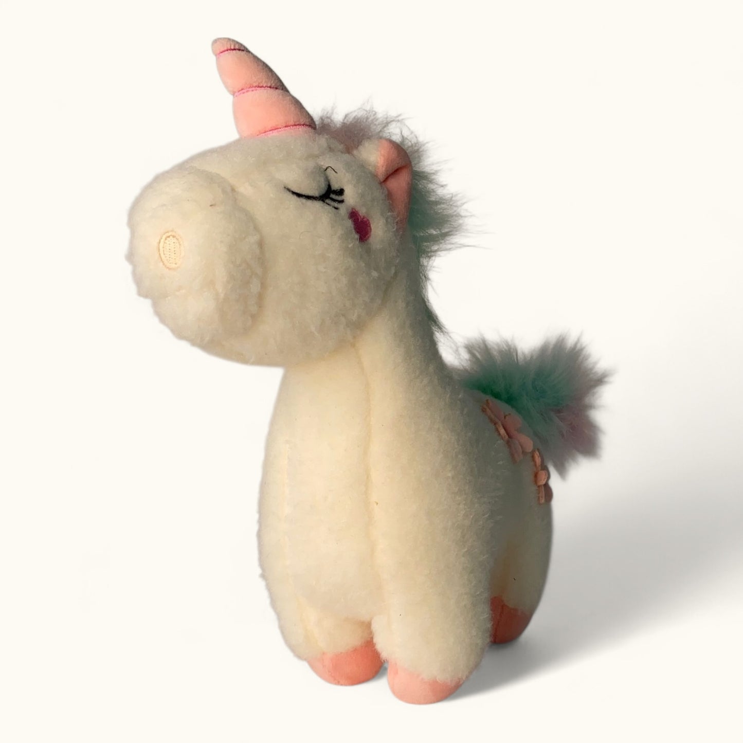 Unicorn plush toy with a pink horn and mane on a white background