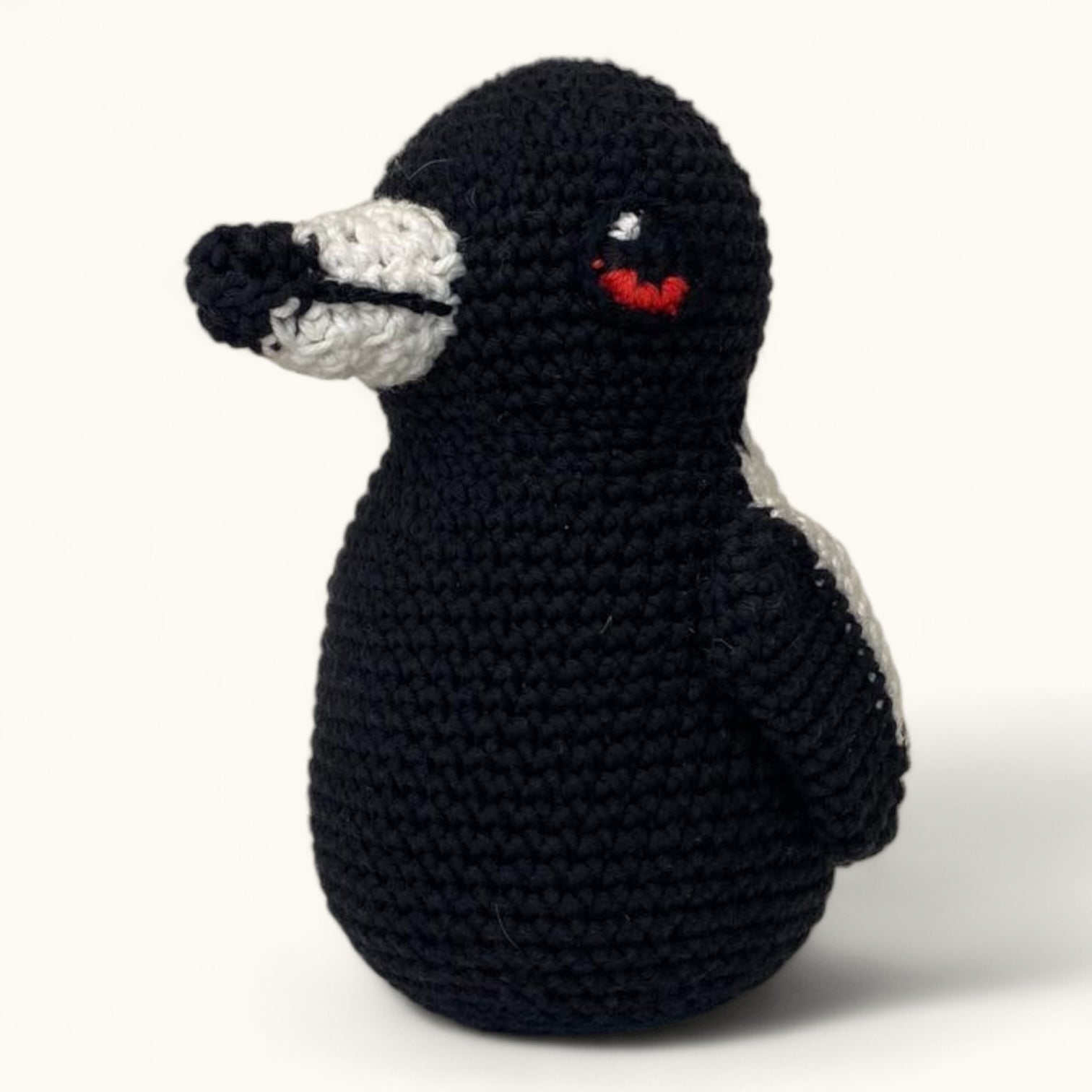 Crocheted penguin toy on a white background
