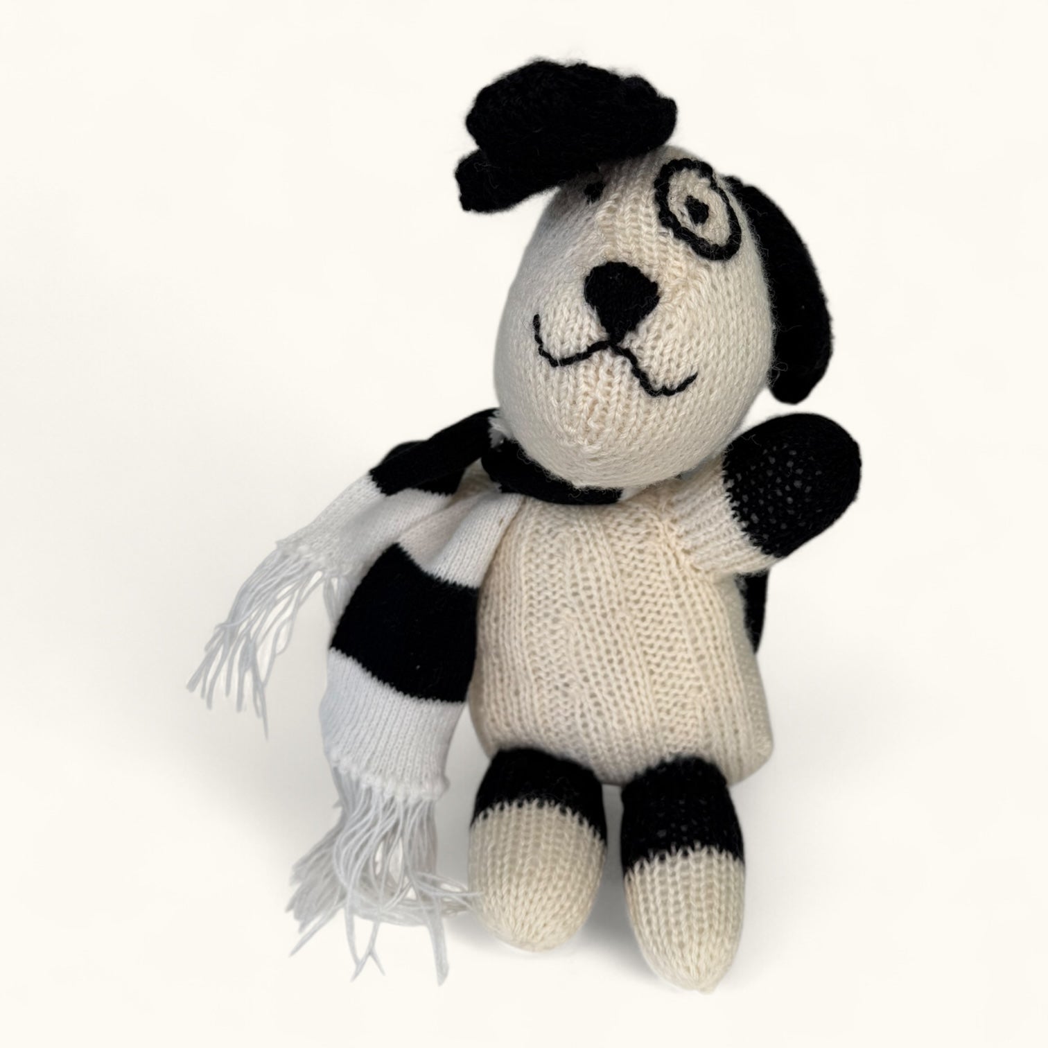 Knitted dog toy with black and white pattern on a white background