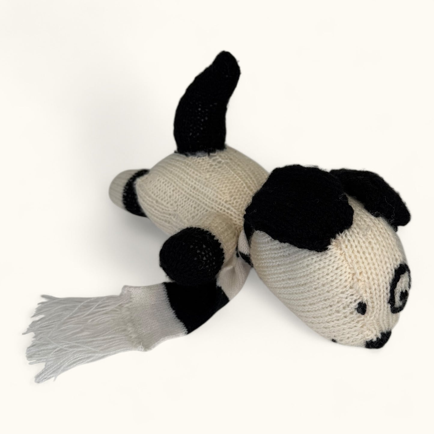 Knitted dog toy with black and white pattern on a white background