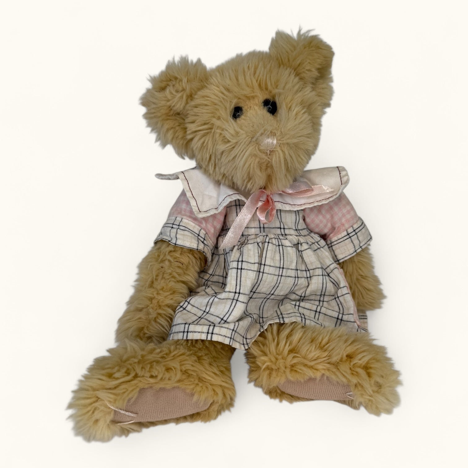 Plush teddy bear wearing a plaid outfit on a white background