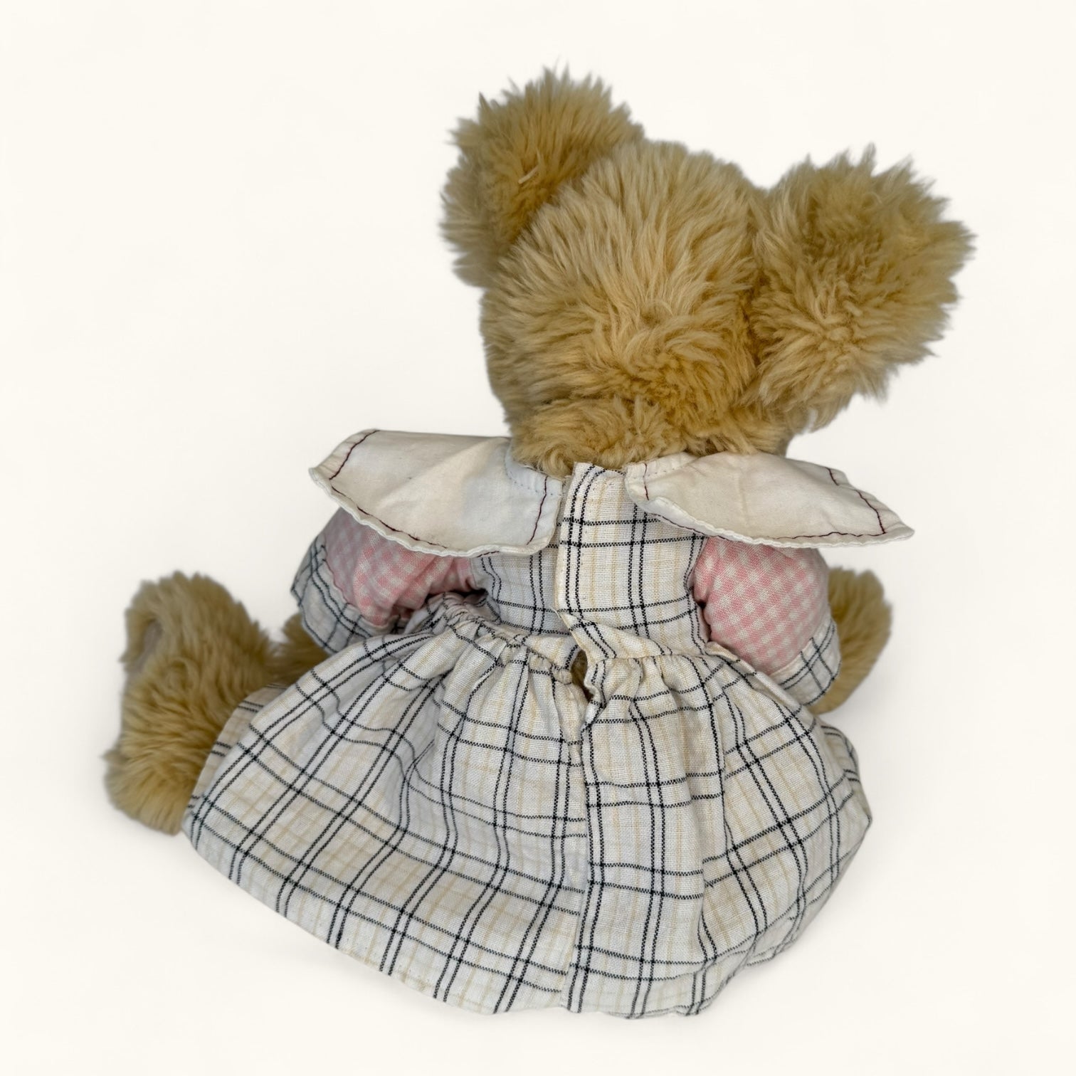 Stuffed teddy bear in a plaid dress on a white background