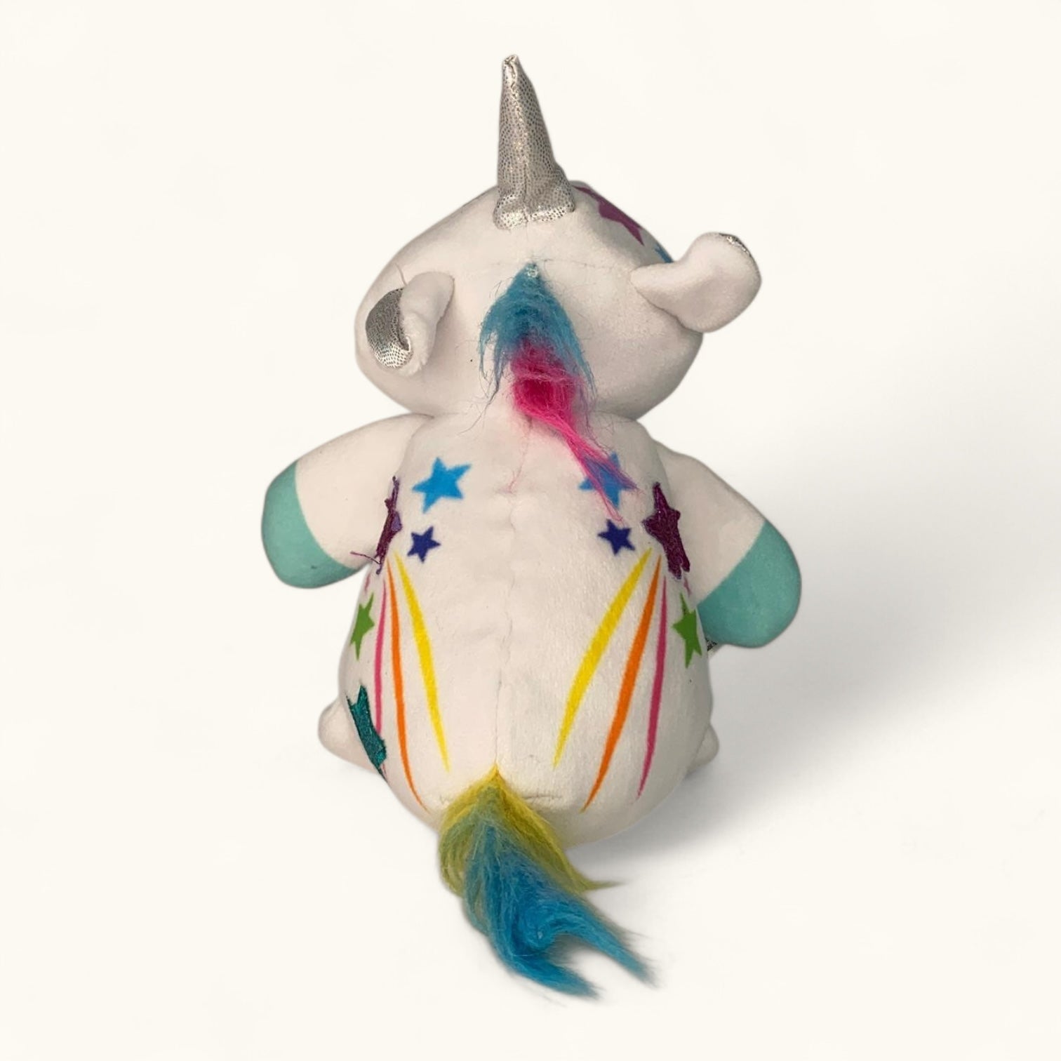 Unicorn plush toy with colorful hair and rainbow on a white background