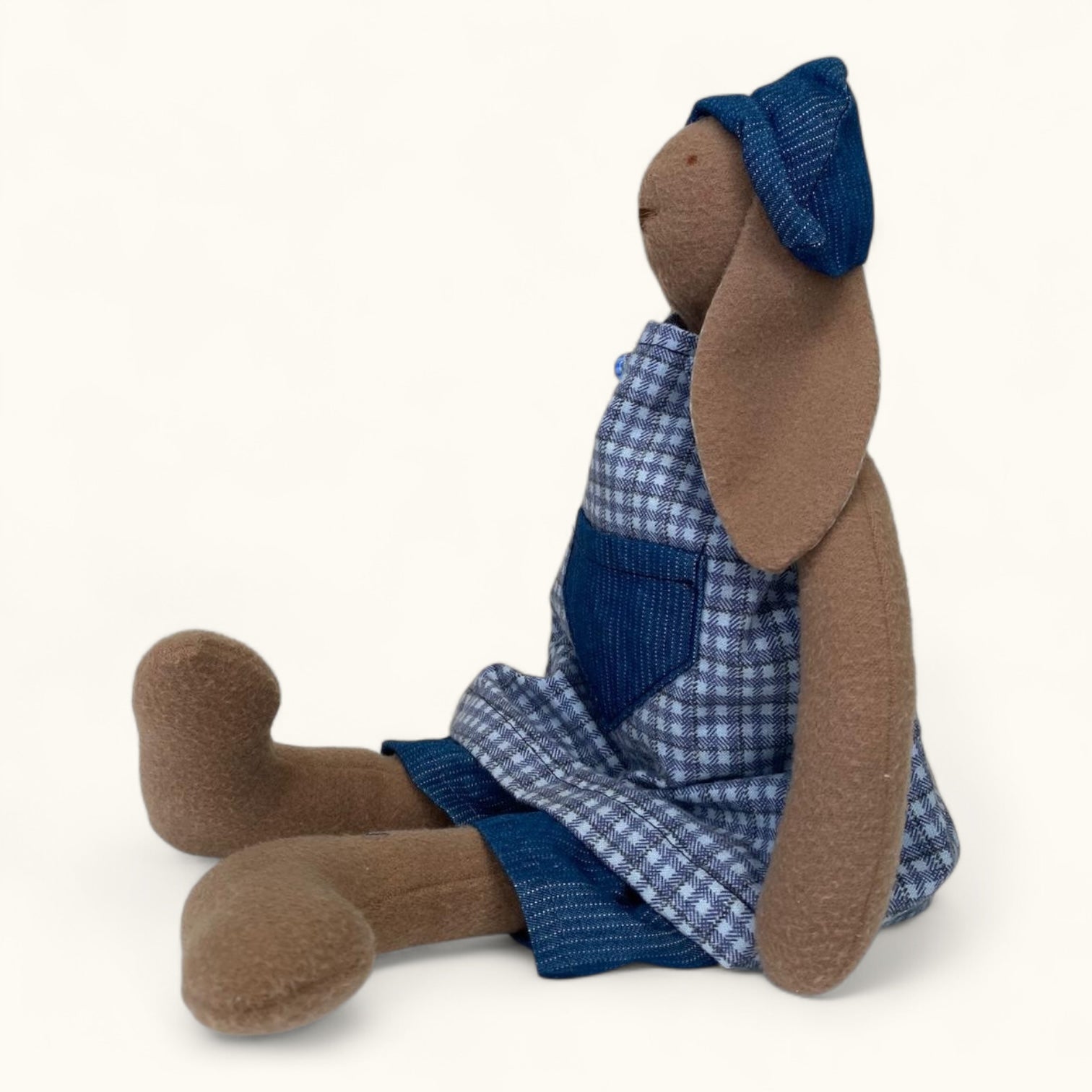 Stuffed animal toy with a blue checkered dress on a white background