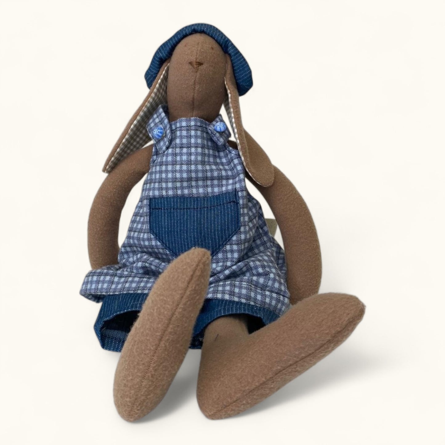 Stuffed toy rabbit wearing a blue checkered outfit on a white background
