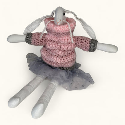 Toy bunny wearing a pink sweater and gray skirt on a white background