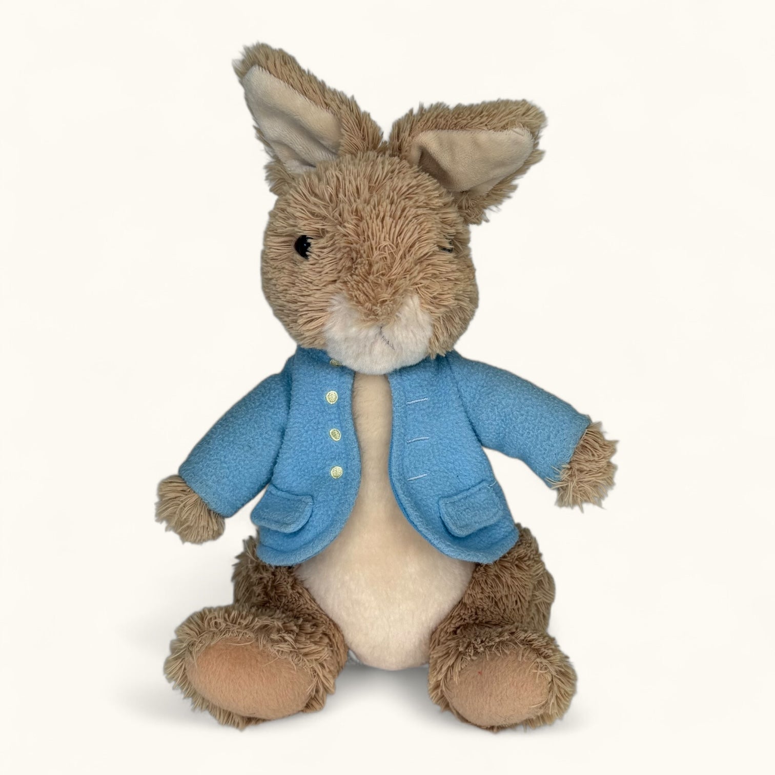 Stuffed toy rabbit wearing a blue coat on a white background