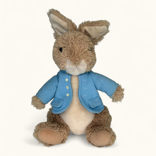 Stuffed toy rabbit wearing a blue coat on a white background