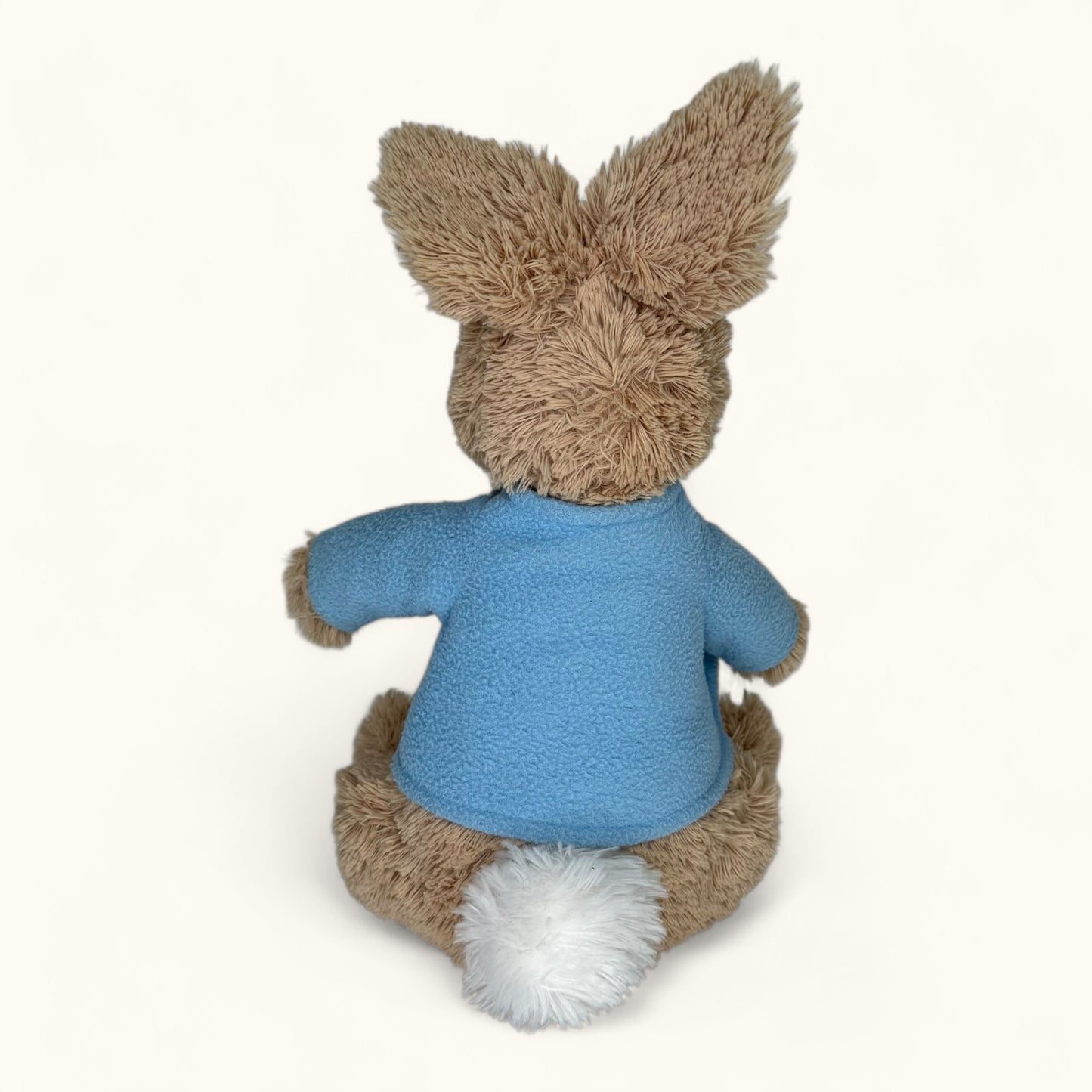 Stuffed animal toy with a blue sweater on a white background