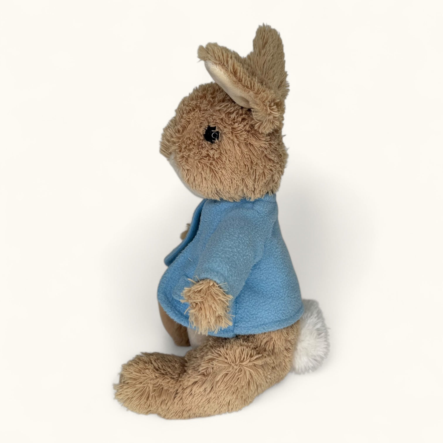 Plush toy rabbit wearing a blue coat on a white background