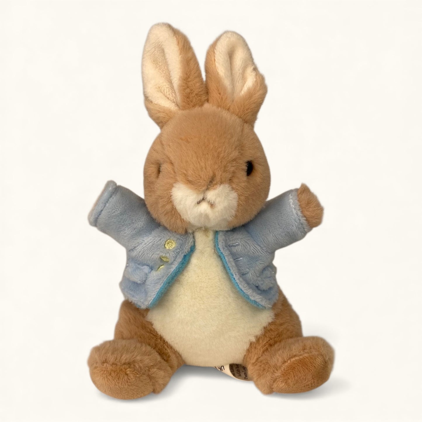 Stuffed rabbit toy with a blue jacket on a white background