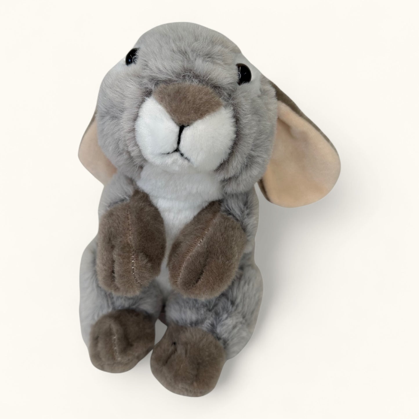 Plush toy rabbit with gray body, brown paws, and white face on a white background