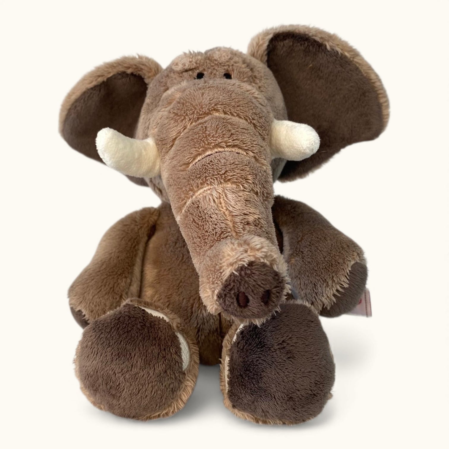 Plush elephant toy with brown fur and white tusks on a white background