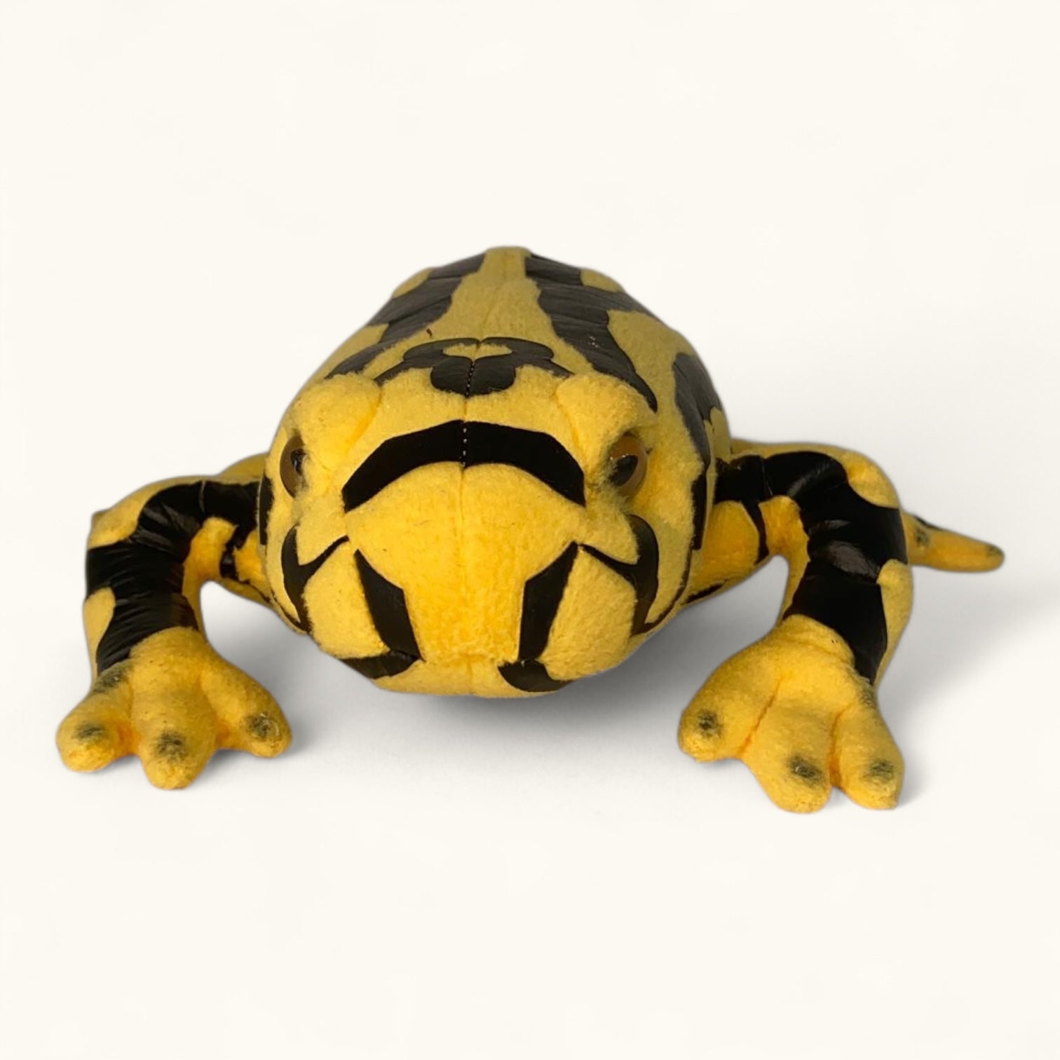 Yellow and black plush frog toy on a white background