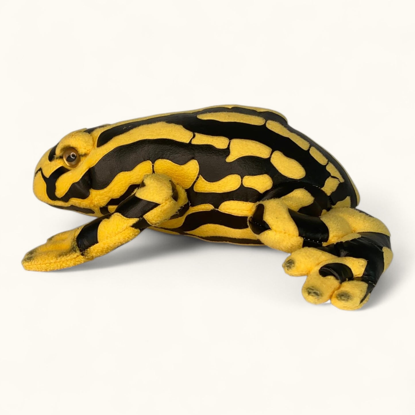 Plush toy frog with black and yellow pattern on a white background