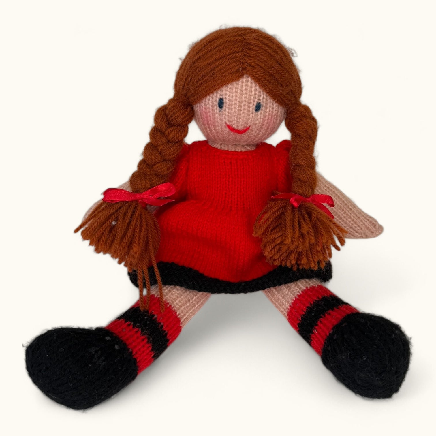 Knitted doll with red dress and brown hair on a white background