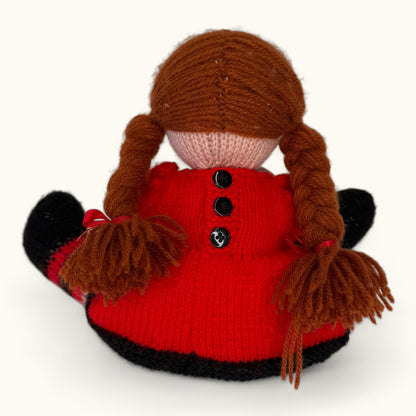 Knitted doll with red outfit and brown hair on a white background