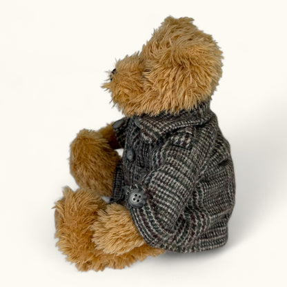Teddy bear wearing a gray coat on a white background