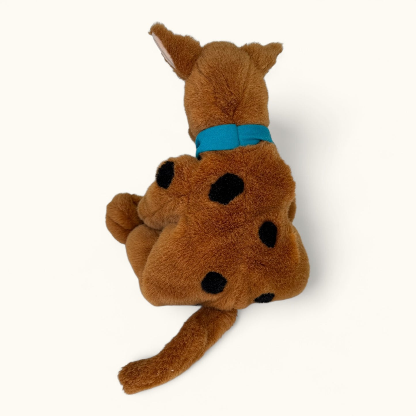 Plush toy resembling a dog with a blue collar on a white background