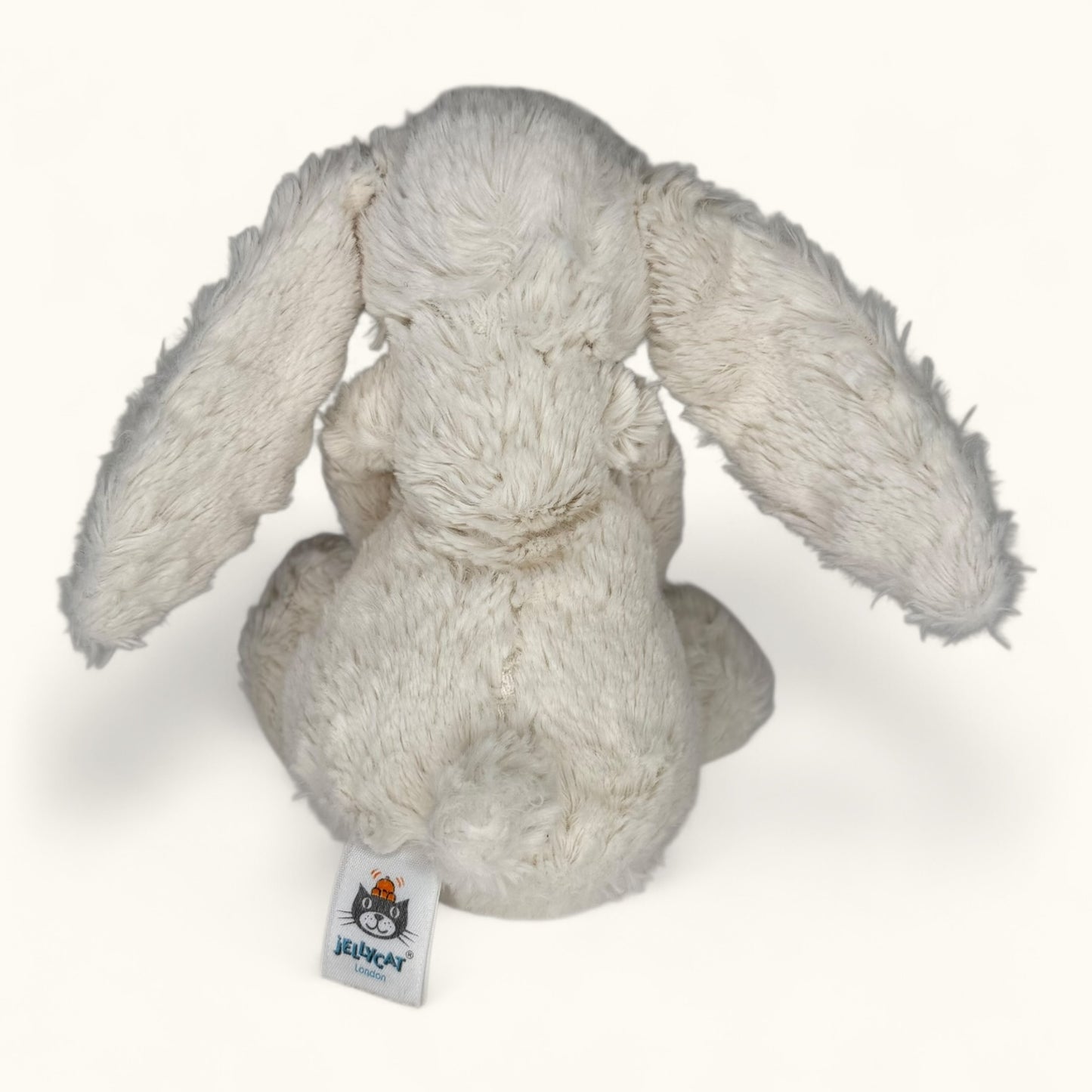 Plush rabbit toy with a visible brand tag on a white background